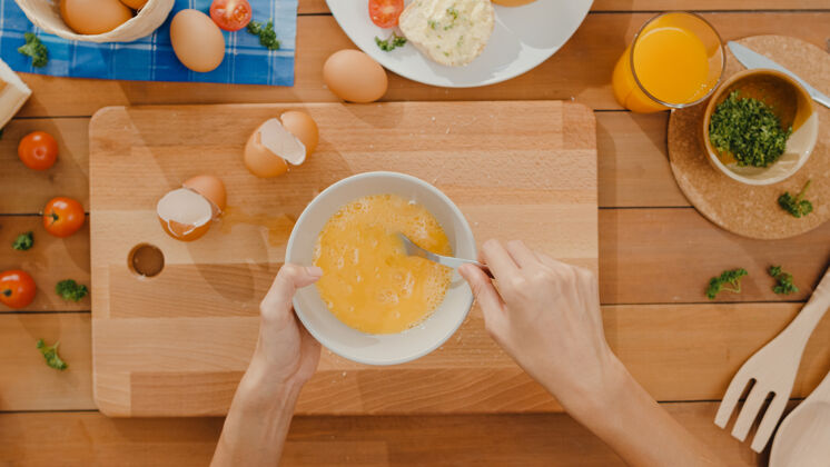 厨师年轻的亚洲女厨师的手把鸡蛋放进陶瓷碗里煮煎蛋厨房面包房西红柿