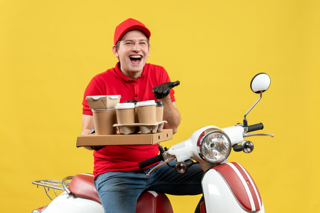 微笑一个穿着红色上衣 戴着帽子手套 戴着医用口罩 坐在滑板车上拿着订单的男人的正视图命令摩托车车辆