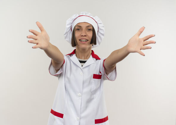 女性身着厨师制服 面带微笑的年轻女厨师向隔离在白色墙壁上的前方伸出双手人人烹饪