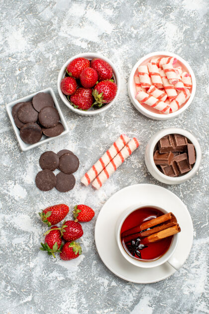 多汁顶视图碗草莓巧克力糖果和肉桂茴香种子茶在灰白色的地面成熟甜点健康