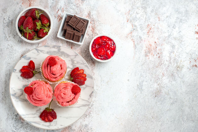 浆果白色表面上有果酱和巧克力棒的粉色草莓蛋糕俯视图草莓棒水果