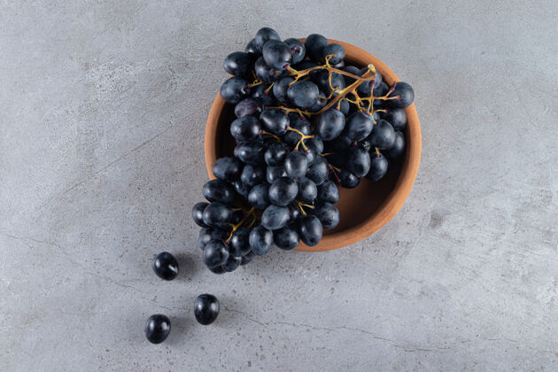 闪亮一簇新鲜的黑葡萄放在泥碗里食物天然串