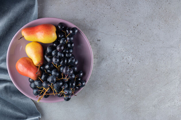 食物石桌上放着一串紫盘子里的红黄梨和葡萄串闪亮天然