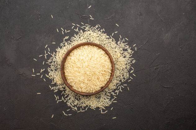 生的深灰色表面上的生米内板顶视图大米食物粉