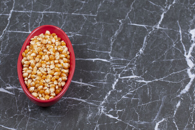 谷类装满玉米种子的红色陶瓷碗俯视图种子配料健康