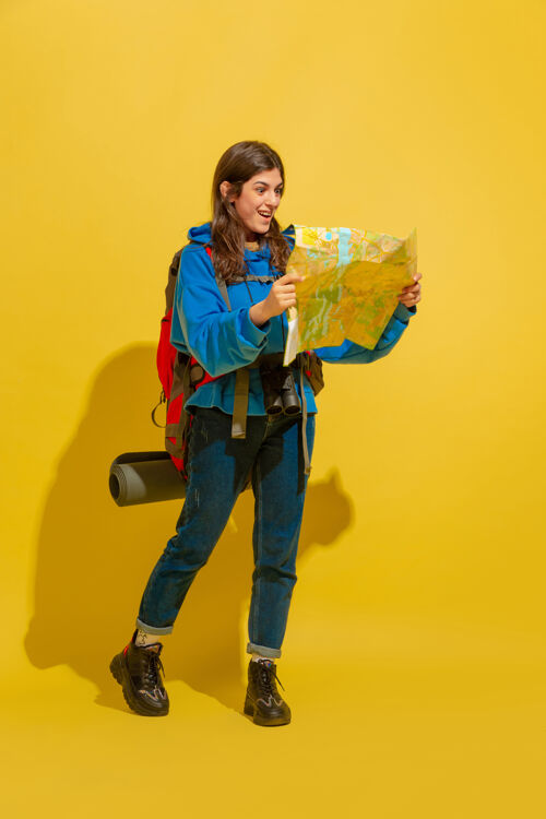 女性微笑 寻找出路一个快乐的年轻高加索旅游女孩的肖像与包和望远镜隔离在黄色的工作室背景准备旅游度假胜地 人类的情感 度假休闲持有手提箱