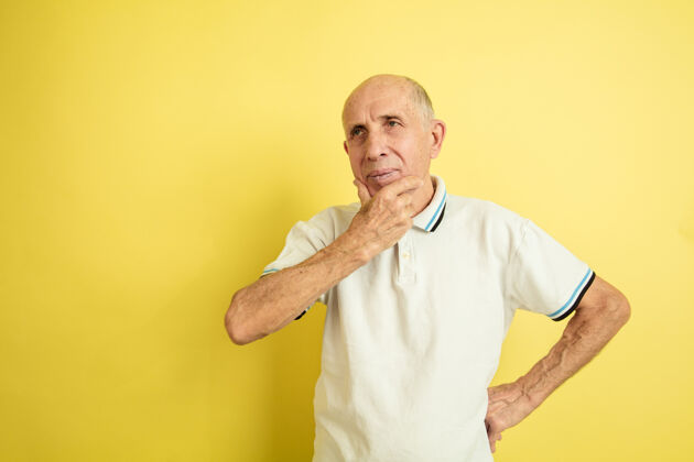 公司体贴黄色工作室背景上的高加索老人肖像美丽的男性情感模型人类情感的概念 面部表情 销售 福利 广告空间健康衬衫工作