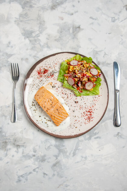 正餐鱼粉和美味沙拉在盘子上的垂直视图 餐具放在染色的白色表面上色斑美味食物