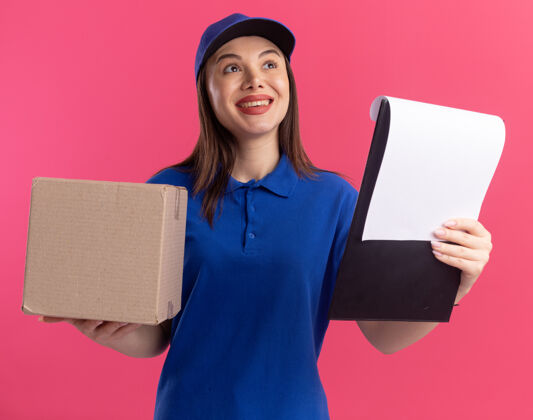 制服一个穿着制服 面带微笑的漂亮女送货员拿着名片盒和剪贴板 看着粉色的一面名片盒粉色微笑