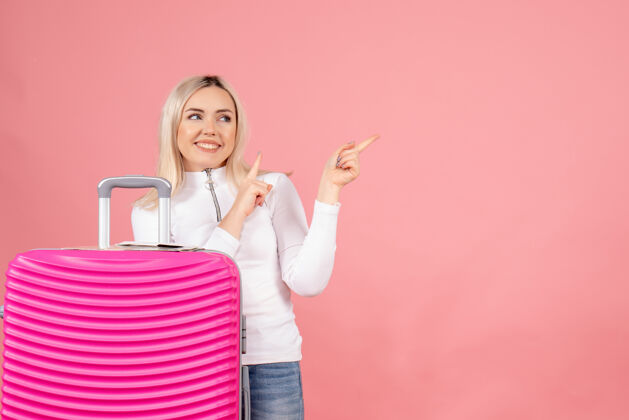 前面正面图美丽的女人 粉色的手提箱指向左边指向左边快乐