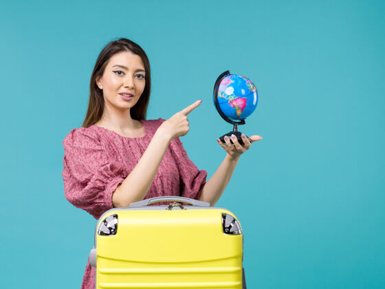 旅行前景度假女抱着小地球仪在蓝色的背景海上度假女旅行避暑地球成人指向