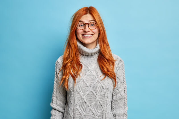 成人可爱的红发女青年 欧式外表 微笑着 穿着暖和的毛衣 表达积极的情绪 听到好消息眼镜红色人