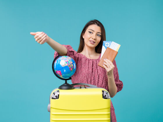 肖像前视图女性在旅行中拿着她的机票在蓝色背景海上旅行度假女性旅行女人前面蓝色