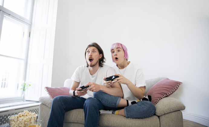 科技可爱的情侣在沙发上玩电子游戏科技乐趣房子