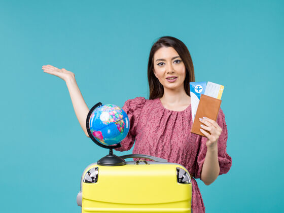 前面前景：旅行中的女性拿着她的机票在蓝色书桌上海上旅行女性旅行度假旅行办公桌旅行抱着