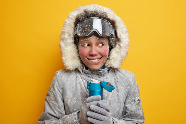 娱乐快乐的女人滑雪板覆盖着白霜试图温暖在寒冷的一天与热饮料穿着冬衣在北极旅行举行的茶保温瓶极端的季节性运动夹克极地阿拉斯加