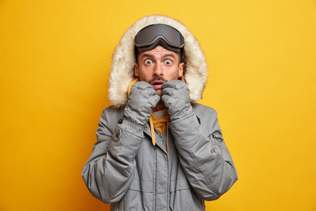 白种人目瞪口呆的白人成年男子盯着被的眼睛穿着保暖的衣服为寒冷季节滑雪护目镜享有最喜爱的爱好和积极的休息人物欧洲兜帽
