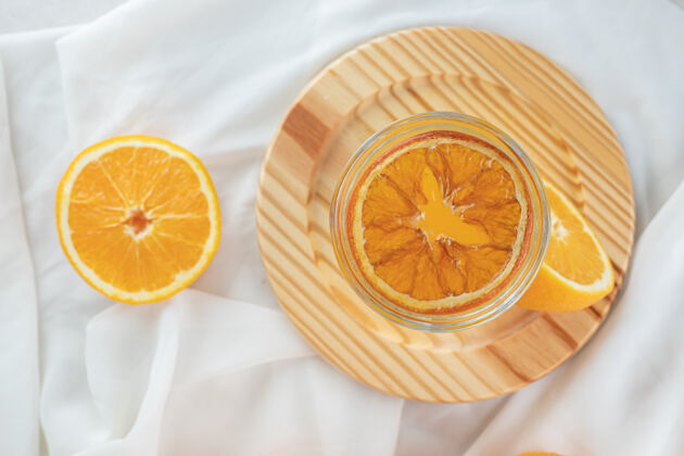 柑橘一杯果汁和新鲜的橙子放在木盘上水果衣服美味