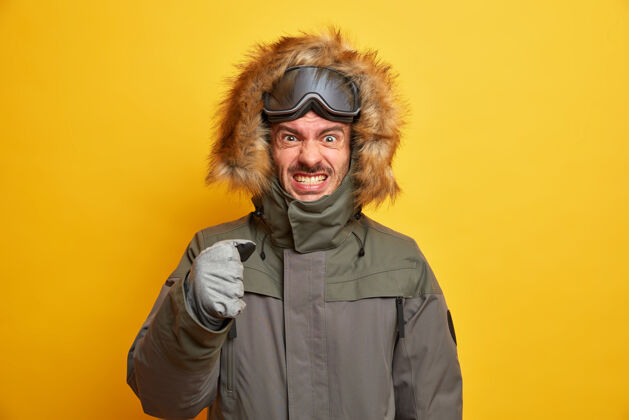 护目镜恼怒的滑雪运动员因愤怒而咬牙切齿在山上度过寒假握拳穿夹克和手套因天气寒冷而不高兴恼怒帅气季节