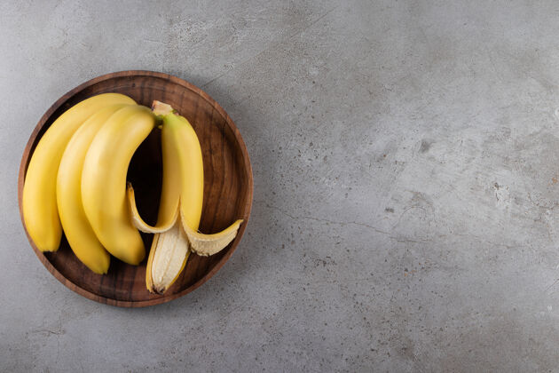 提神成熟的香蕉放在木盘上 放在大理石表面丰盛饮食天然