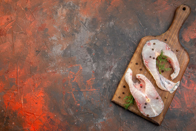 生锈新鲜的生鱼肉和胡椒粉在混合色表面的木制砧板上的俯视图年份切割混合