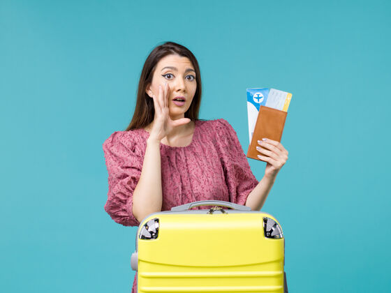 视图前景度假中的女性拿着她的钱包和蓝色背景的机票旅行旅行女性暑假前面票蓝色