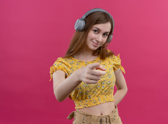 自信自信的年轻女孩戴着耳机 指着孤立的粉色空间与复印空间复制粉色女孩