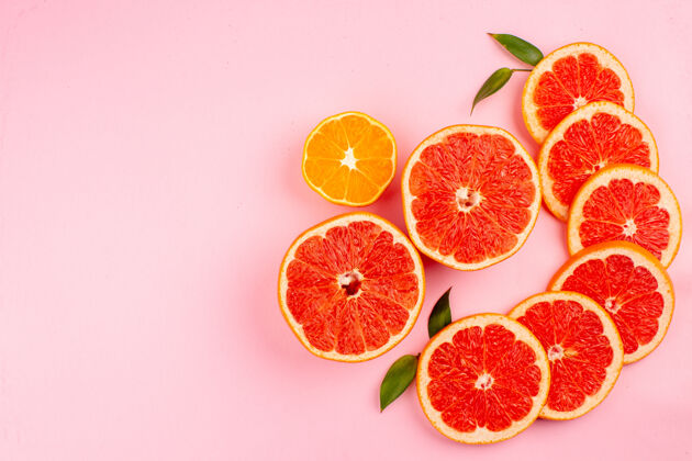 果汁粉红色表面上美味的葡萄柚和多汁的水果片的俯视图健康成熟食品