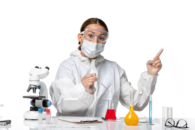 视图前视图穿着防护服 戴着口罩的女医生正在用浅白色背景的冠状病毒大流行病毒的解决方案工作工作女医生实验室外套