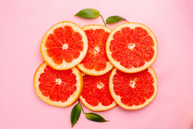 果汁粉红色表面上美味的葡萄柚和多汁的水果片的俯视图新鲜切片可食用水果