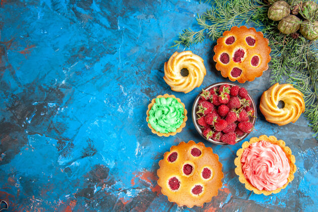 饼干树莓蛋糕 饼干 小馅饼 蛋卷和蓝色表面草莓碗的俯视图蛋卷假日草莓