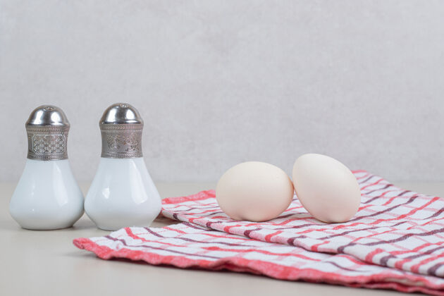 生的两个新鲜的鸡蛋放在桌布上鸡蛋盐生的