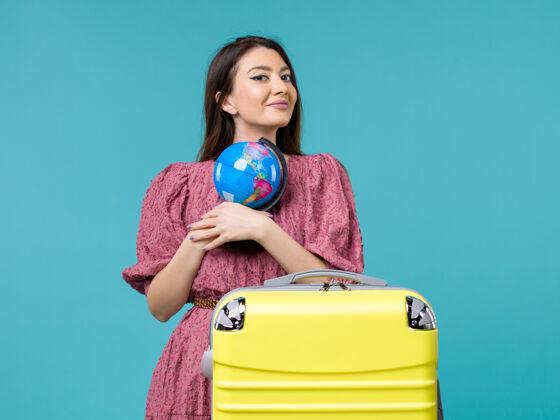 风景前视图女性在旅行中拿着地球仪在蓝色的背景上旅行旅行旅行旅行旅行旅行女人海旅行微笑假期
