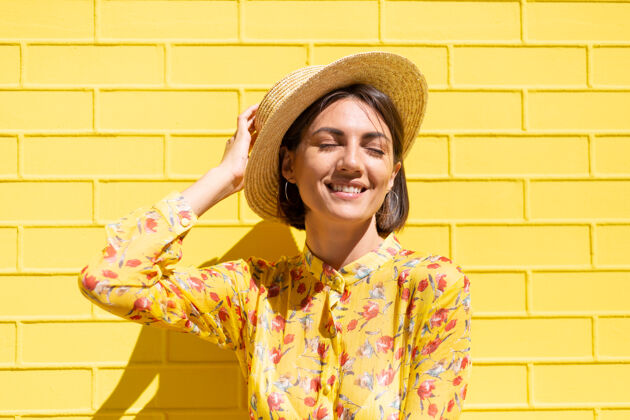 有趣黄砖墙上戴着黄色夏装和帽子的女人沉着而积极 享受着阳光明媚的夏日休闲年轻模型