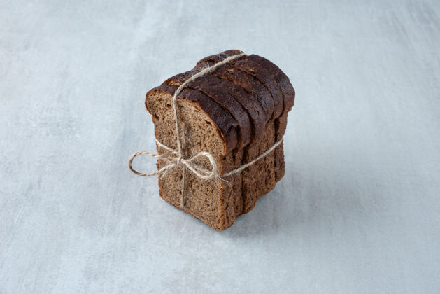 切片黑吐司面包用绳子绑在石头面上面包房黑麦美味