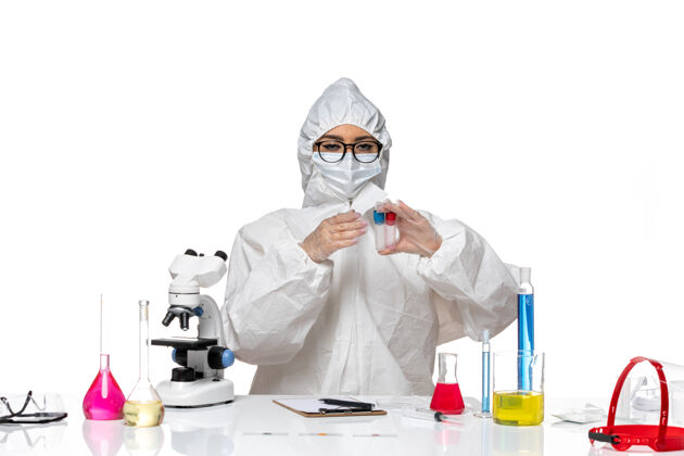 白色正面图身着特殊防护服的女化学家手持白色背景上的空烧瓶健康病毒化学冠状病毒套装口罩医生