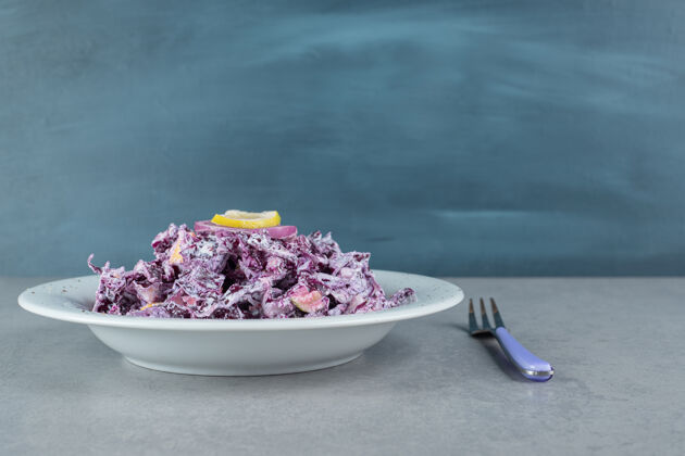晚餐切碎的紫洋葱和卷心菜沙拉放在一个白色的陶瓷盘子里美味早午餐混凝土