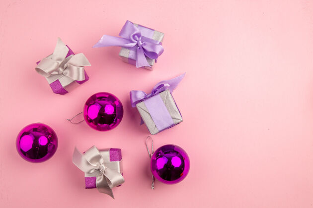 花顶视图的小礼物与圣诞树玩具在粉红色的表面爱树花