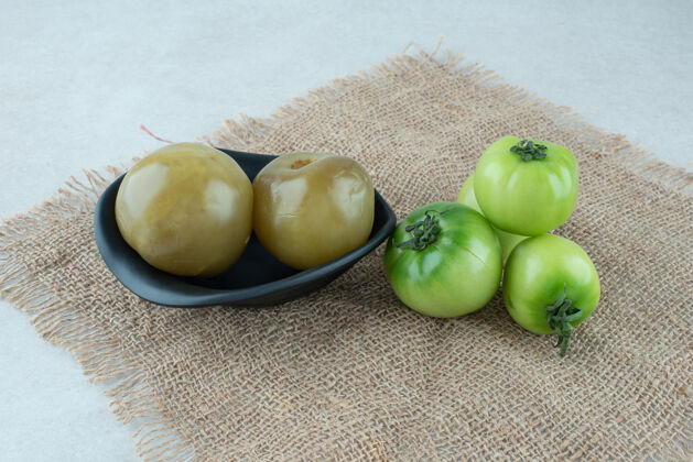 绿色新鲜的和一碗腌青番茄放在粗麻布上番茄发酵有机
