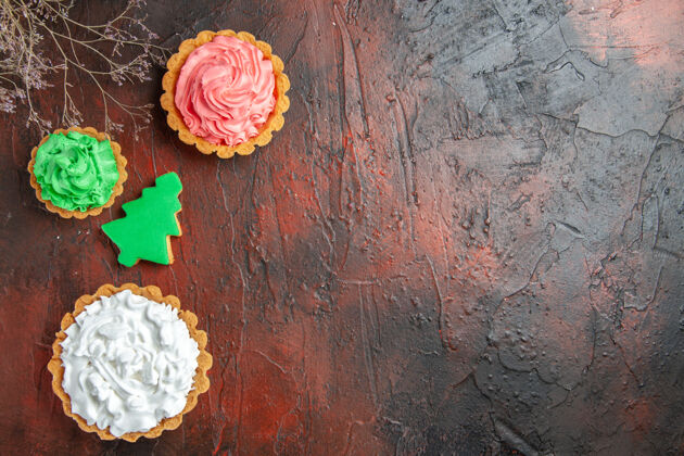 不同的圣诞树饼干和深红色表面上不同的馅饼俯视图年龄生锈旧的