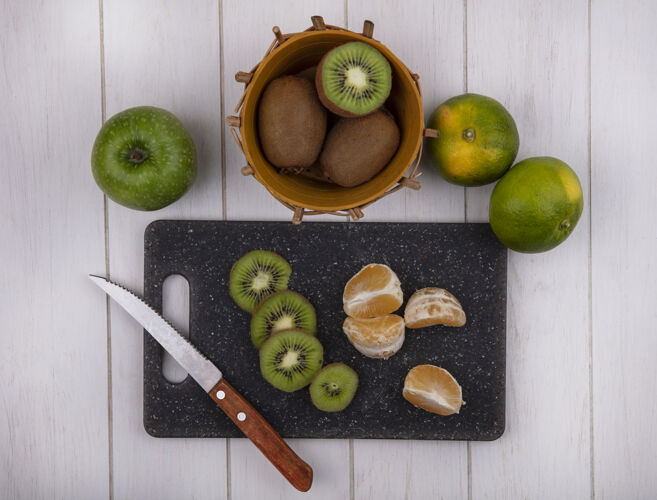 苹果俯瞰切菜板上的橘子片 篮子里放着猕猴桃 绿橘子和苹果观点水果猕猴桃