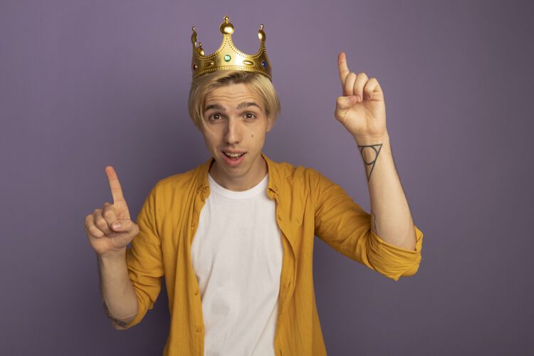 紫色令人印象深刻的年轻金发男子穿着黄色t恤和皇冠点上孤立的紫色皇冠印象尖
