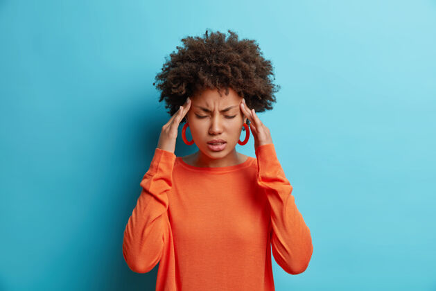 不满意沮丧的年轻美国黑人妇女头痛的照片双手放在太阳穴忍受难以忍受的偏头痛感觉生病健康
