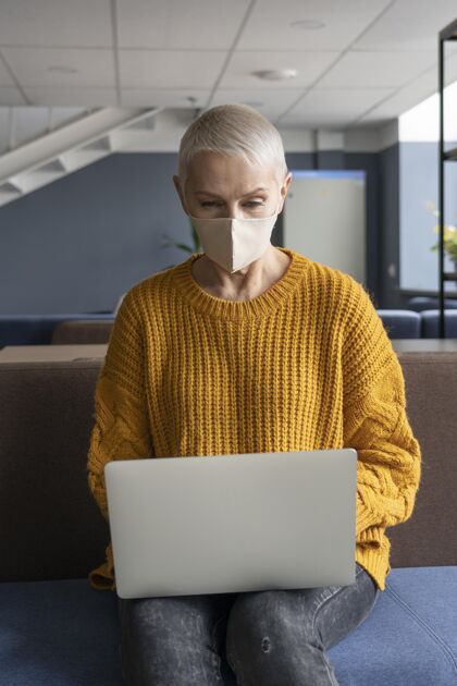 社交距离戴着医用面罩上班的女人人办公室工作