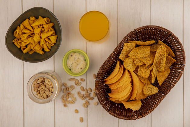 罐子在米色木桌上的玻璃罐上 桶里放着一杯橙汁和松子酱的美味脆薯片的俯视图美味视图顶部