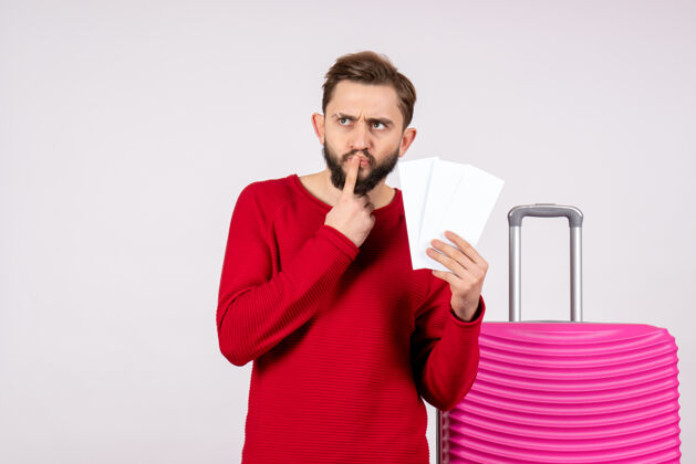 机票正面图：年轻男性 带着粉色包 手持飞机票 乘坐白墙航程航班 旅游度假情感照片成人度假飞行