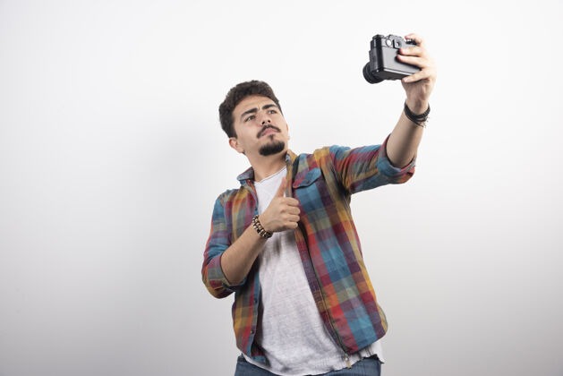 装备用相机以积极的态度拍摄他的自拍年轻男人姿势