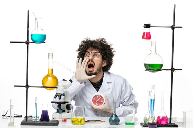 男科学家前视图穿着医疗服的男科学家拿着红色的时钟 在空白处尖叫实验室医学实验室