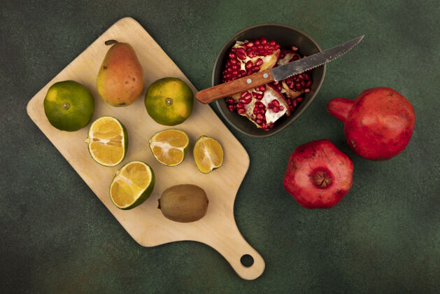 观木制菜板上有机橘子的俯视图 菜刀上放着美味的水果 如梨 猕猴桃和石榴食物木头新鲜