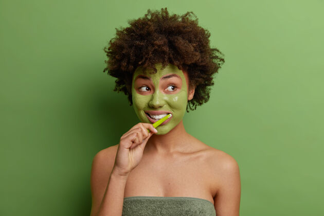 清洁年轻的非洲裔美国妇女的照片应用绿色面罩刷牙用牙刷女人一粘土